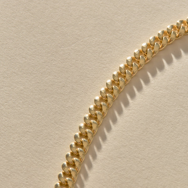 Gold chain bracelet on a beige background