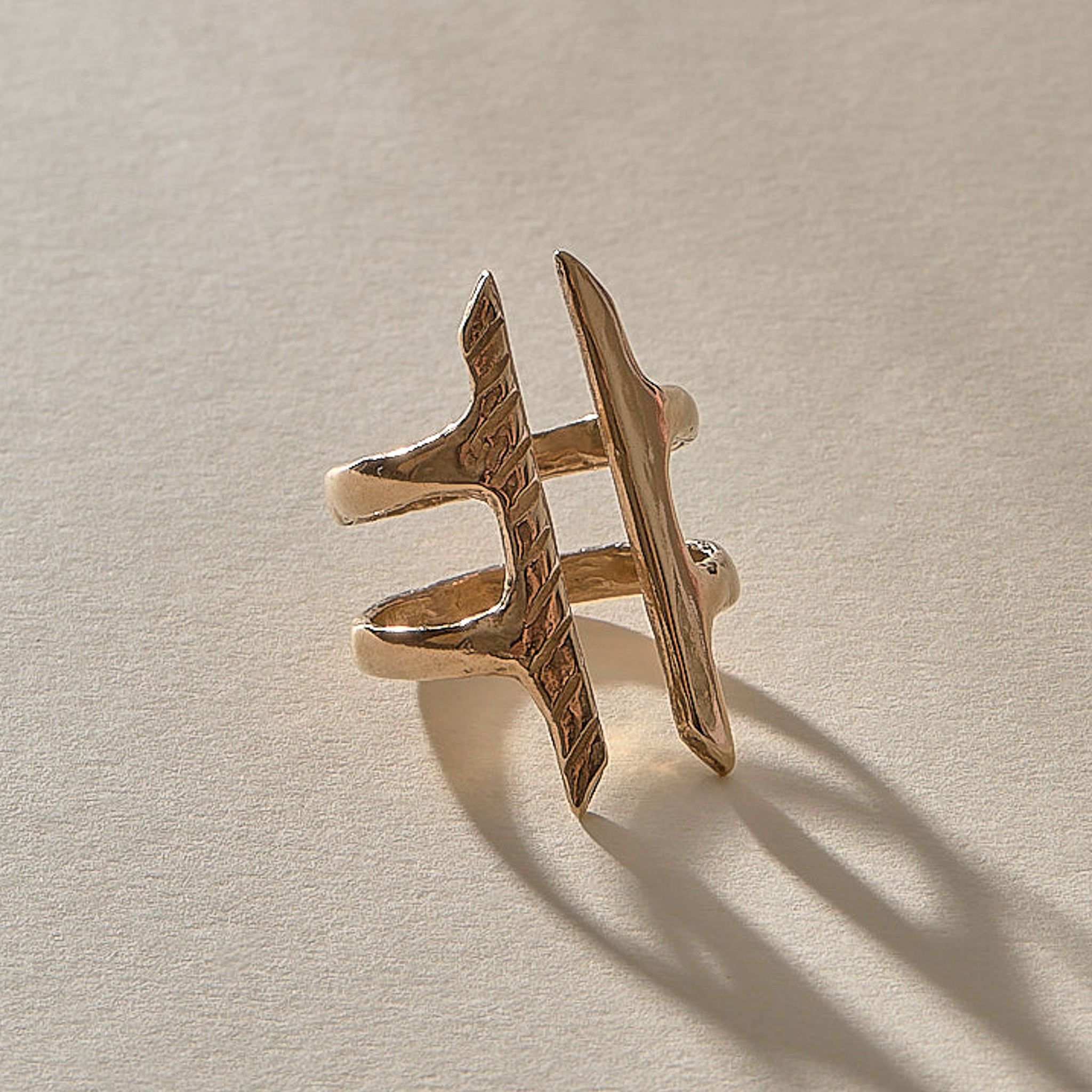 Akash Shield Statement Ring in recycled bronze at an angle, showing the carved shield bars and open design.