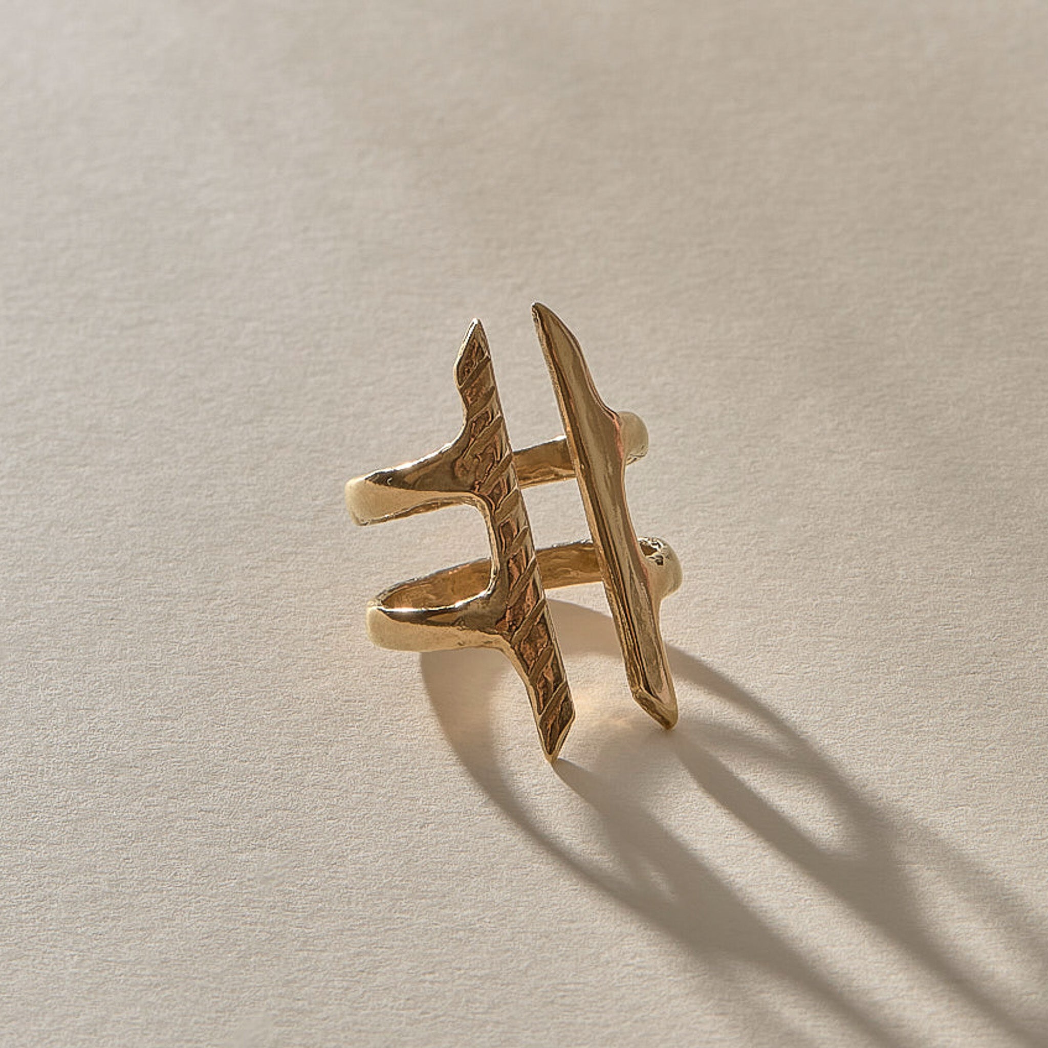 Akash Shield Statement Ring in solid recycled gold at an angle, showing the carved shield bars and open design.