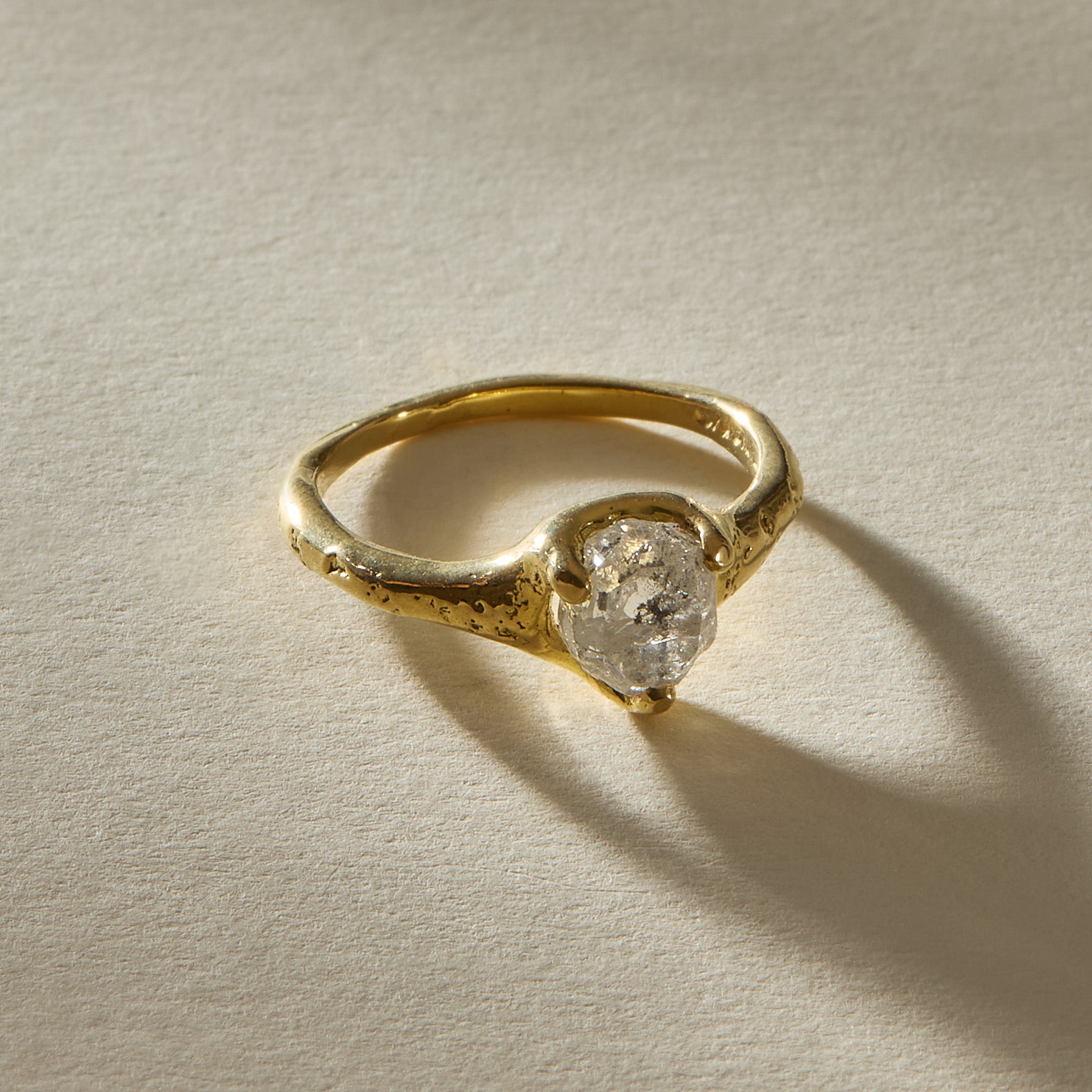 Amara raw diamond ring at an angle, showing the textured shoulders of the 18k gold band.