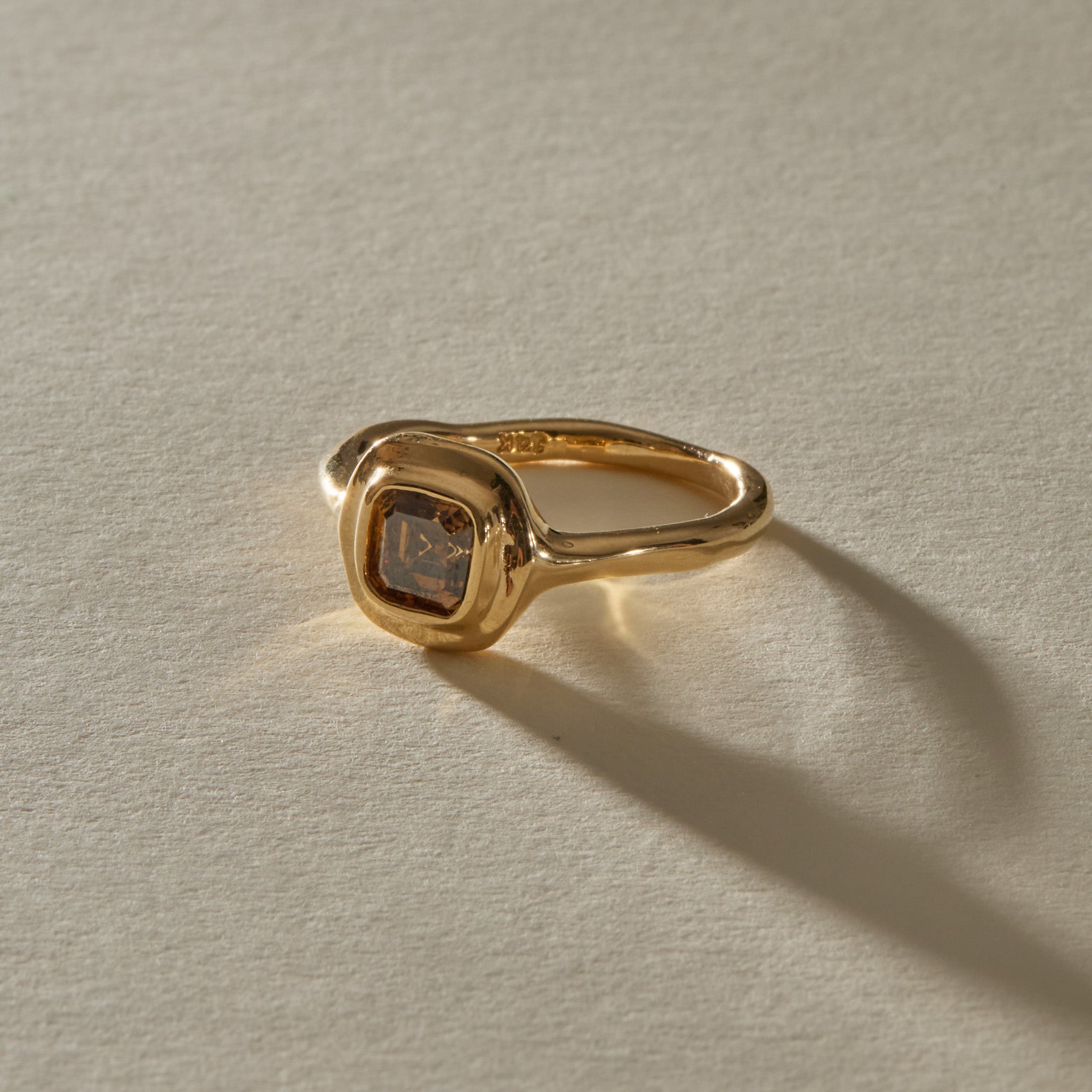 Ambre Ring in 14k gold at an angle, with the smooth band sweeping into the champagne diamond setting.