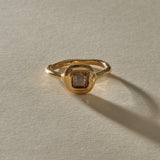 Ambre champagne diamond ring from the front, showing the square step cut stone in its rounded gold bezel.