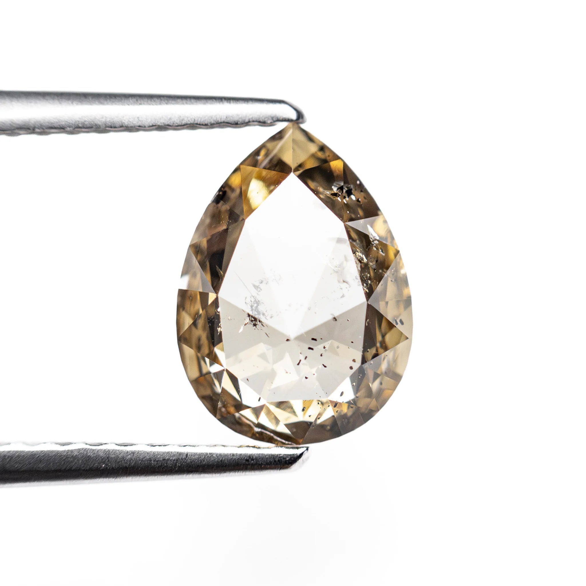 The 1.35ct champagne salt and pepper pear rose cut diamond held in tweezers before setting.