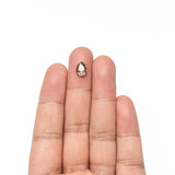 The loose pear rose cut diamond resting on fingertips to show its size.