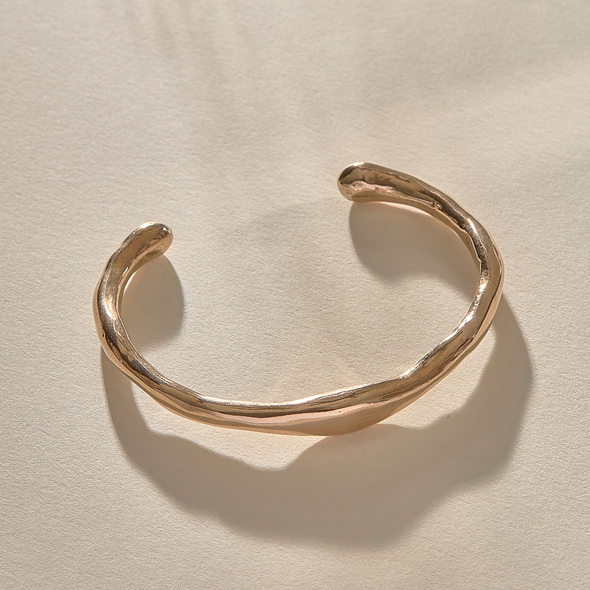 Bone Cuff Bracelet in bronze at an angle, showing the open ends and hand-carved texture.