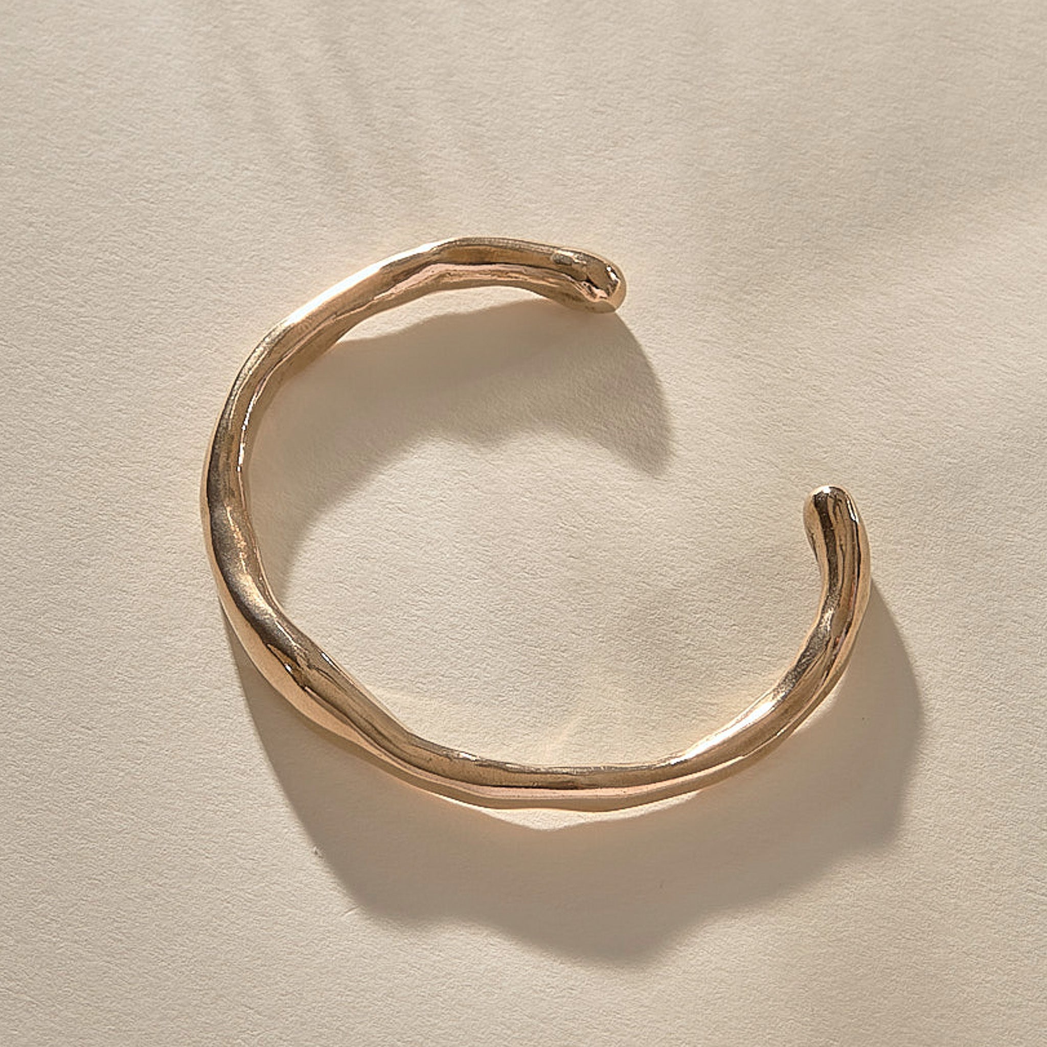 Bone Cuff Bracelet in bronze from the side, the band thickening and thinning along its curve.