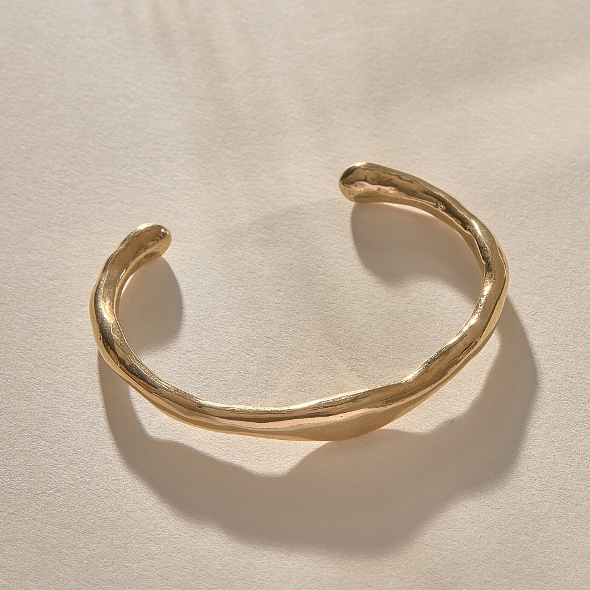 Bone Cuff Bracelet in gold at an angle, showing the open ends and hand-carved texture.