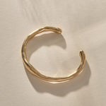 Bone Cuff Bracelet in gold from the front, the band thickening and thinning along its curve.