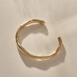 Bone Cuff Bracelet in gold from the front, the band thickening and thinning along its curve.