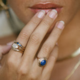 Model with her fingers to her lips, wearing the Cleo Lapis Lazuli Amulet Ring with stacked rings.