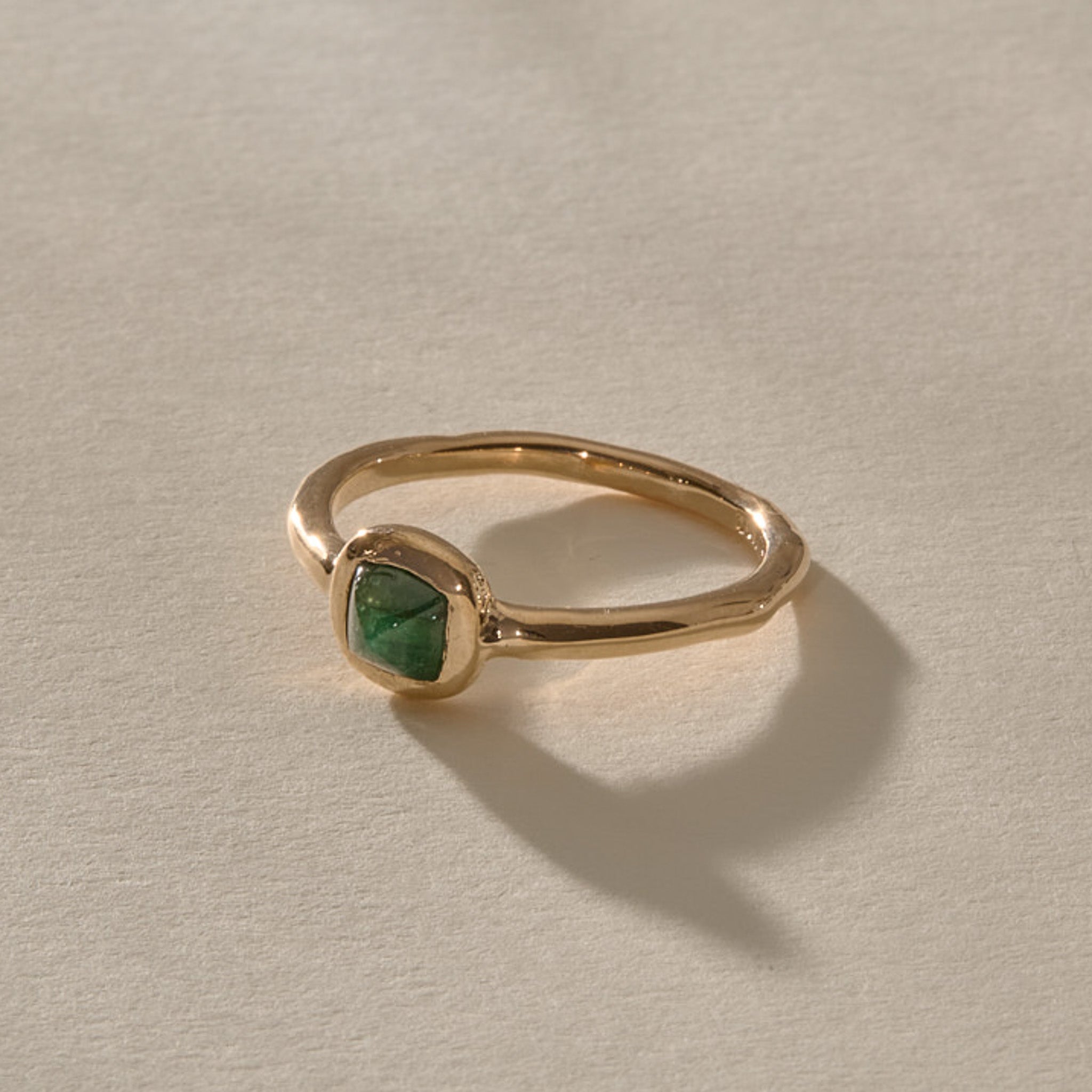 Cosmos Emerald Ring in solid recycled gold at an angle, showing the green emerald cabochon.