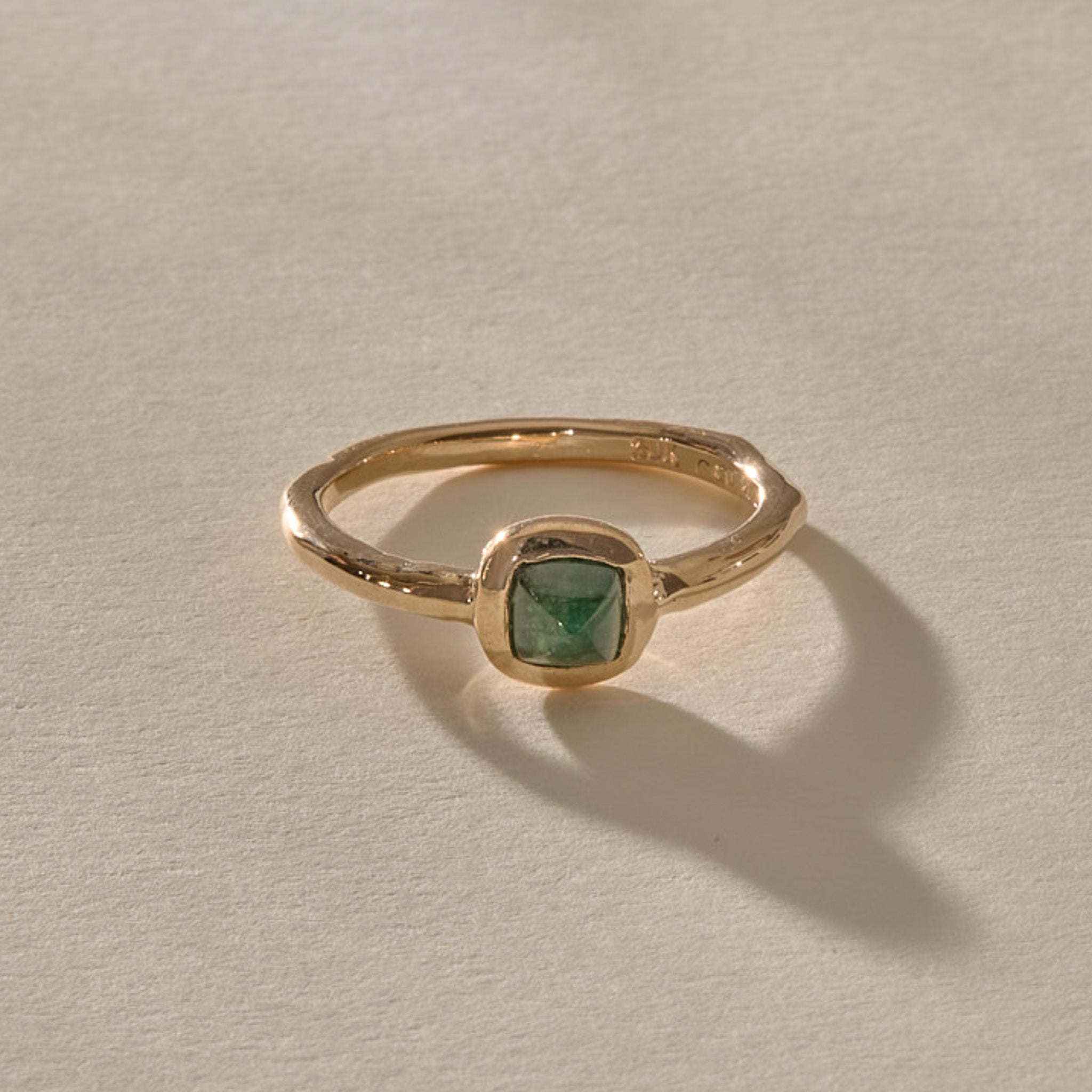 Cosmos Emerald Ring in solid recycled gold, a square sugarloaf emerald cabochon in a bezel on an organic band.