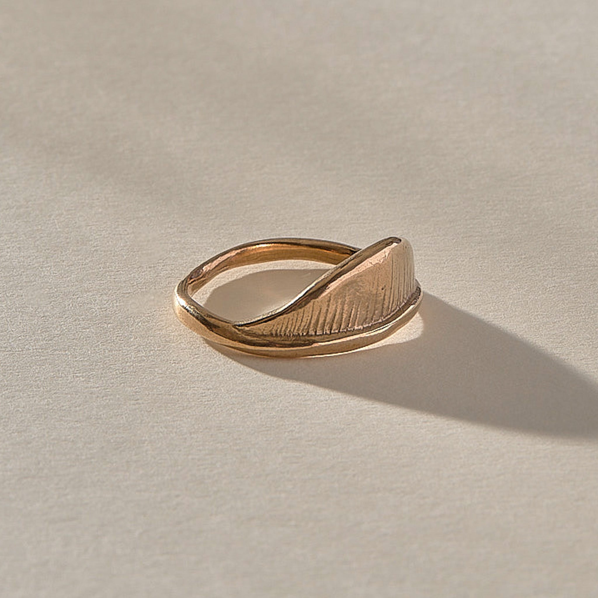 Devotions Wave Ring in recycled bronze at an angle, showing the carved wave face.
