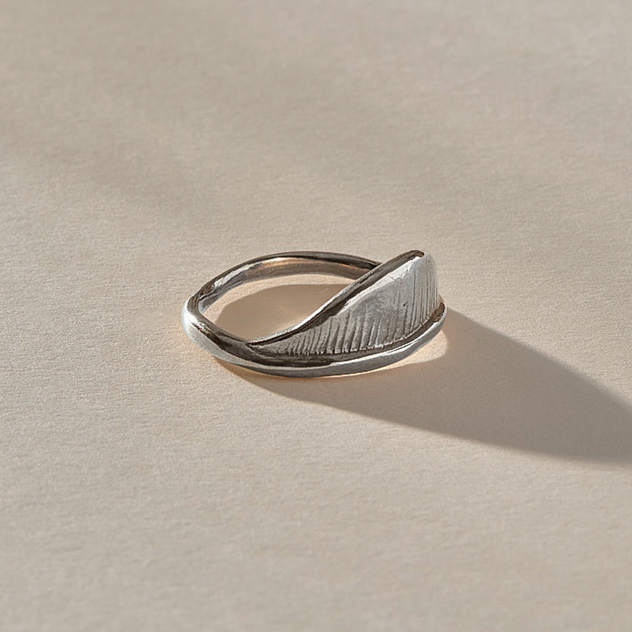 Devotions Wave Ring in recycled sterling silver at an angle, showing the fine carved lines across the wave.