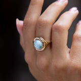 Hand against a dark background wearing the Elysian Larimar Signet Ring.
