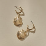 Elysian Shell Hoop Earrings in solid recycled gold, cast scallop shells on slim hoops, laid flat.