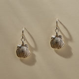 Elysian Shell Hoop Earrings in sterling silver hanging side by side, scallop shells below small hoops.