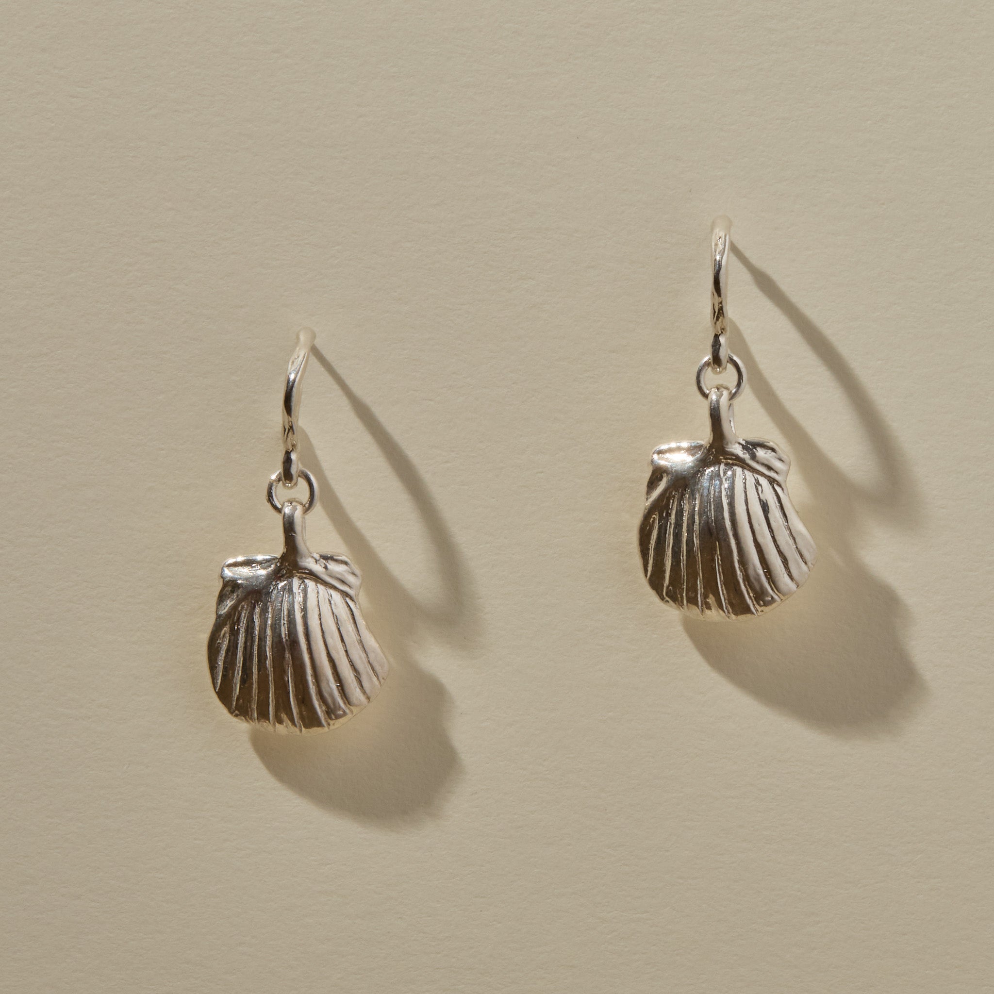 Elysian Shell Hoop Earrings in sterling silver, a pair of ribbed scallop shells catching the light.