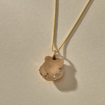 Back of the Elysian Shell Necklace pendant in bronze, showing the smooth inside of the shell.