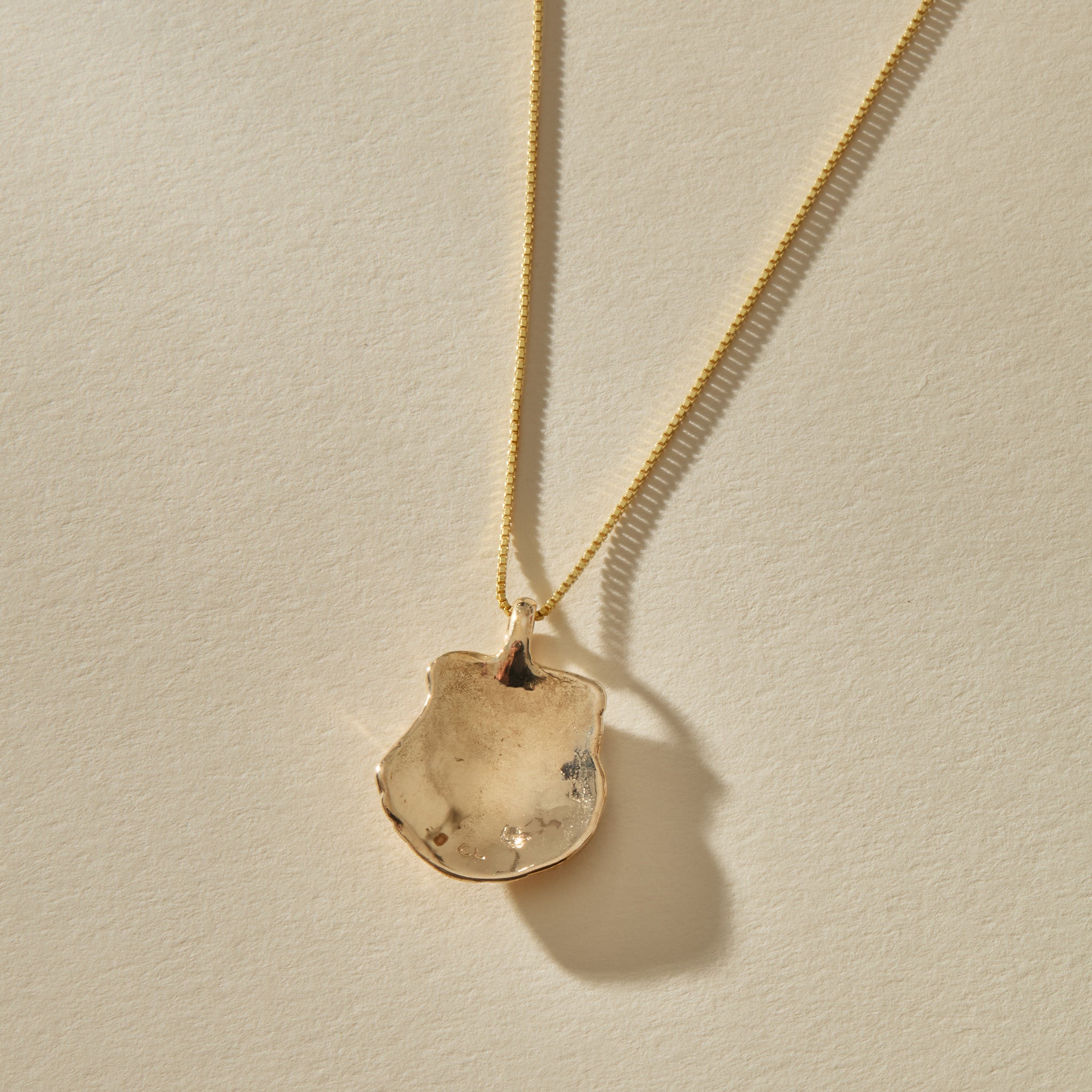 Back of the Elysian Shell Necklace pendant in gold, showing the smooth inside of the shell.