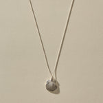 Elysian Shell Necklace in sterling silver, the scallop shell pendant hanging from its box chain.