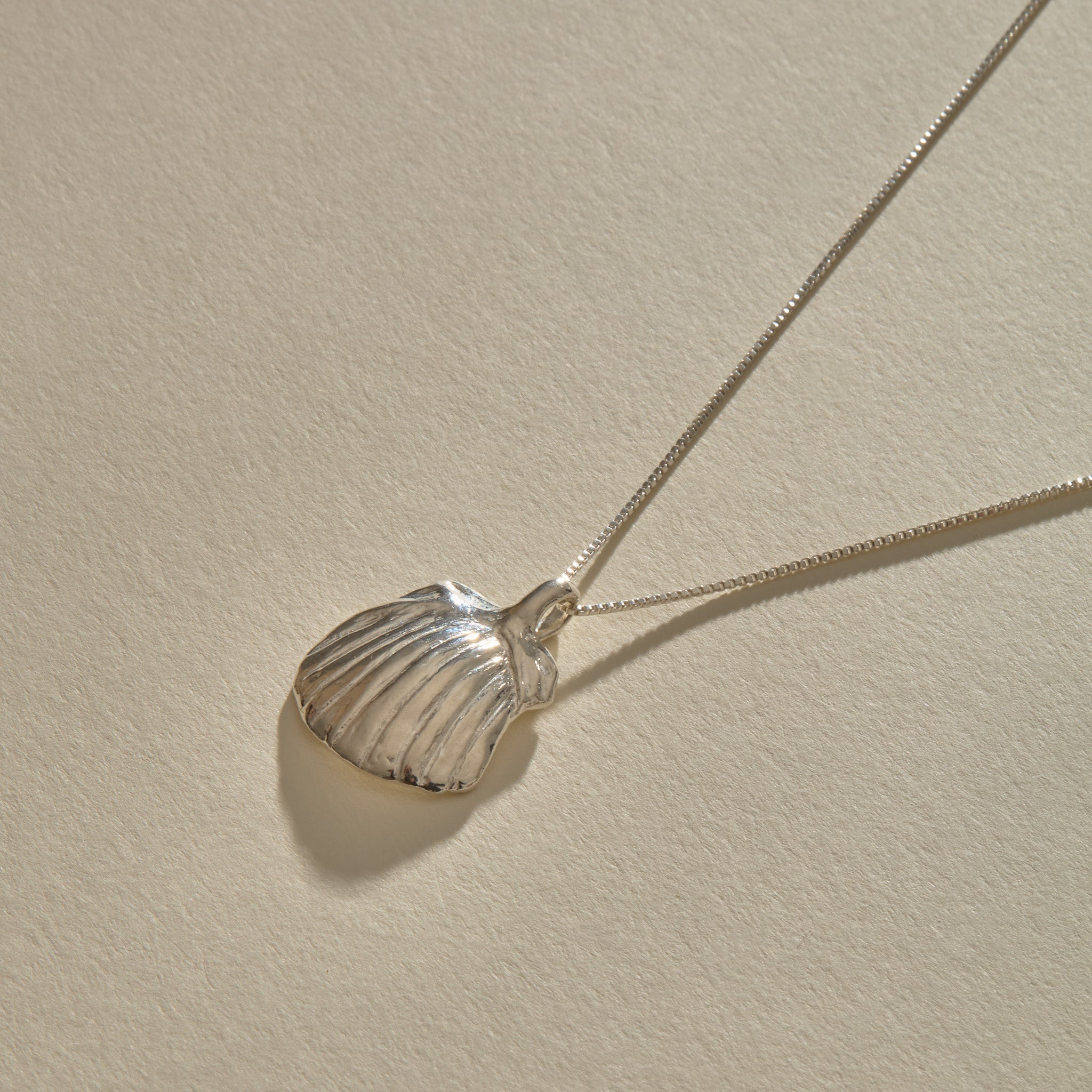 Elysian Shell Necklace in sterling silver, the ribbed scallop shell pendant at an angle.