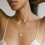 Elysian Shell Necklace worn at the collarbone with a white top.