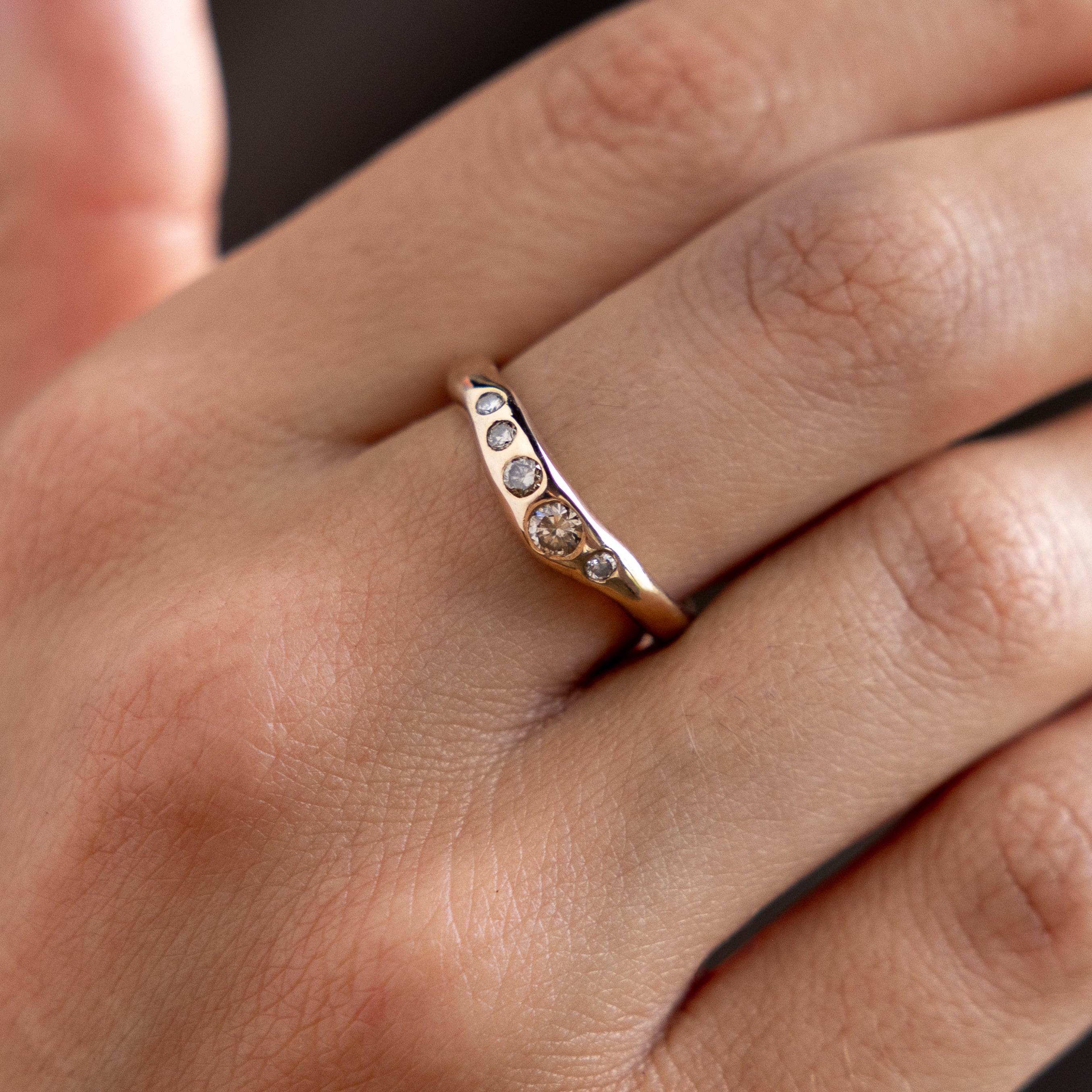 Close up of a hand wearing the Eros Five-Stone Champagne Diamond Band.