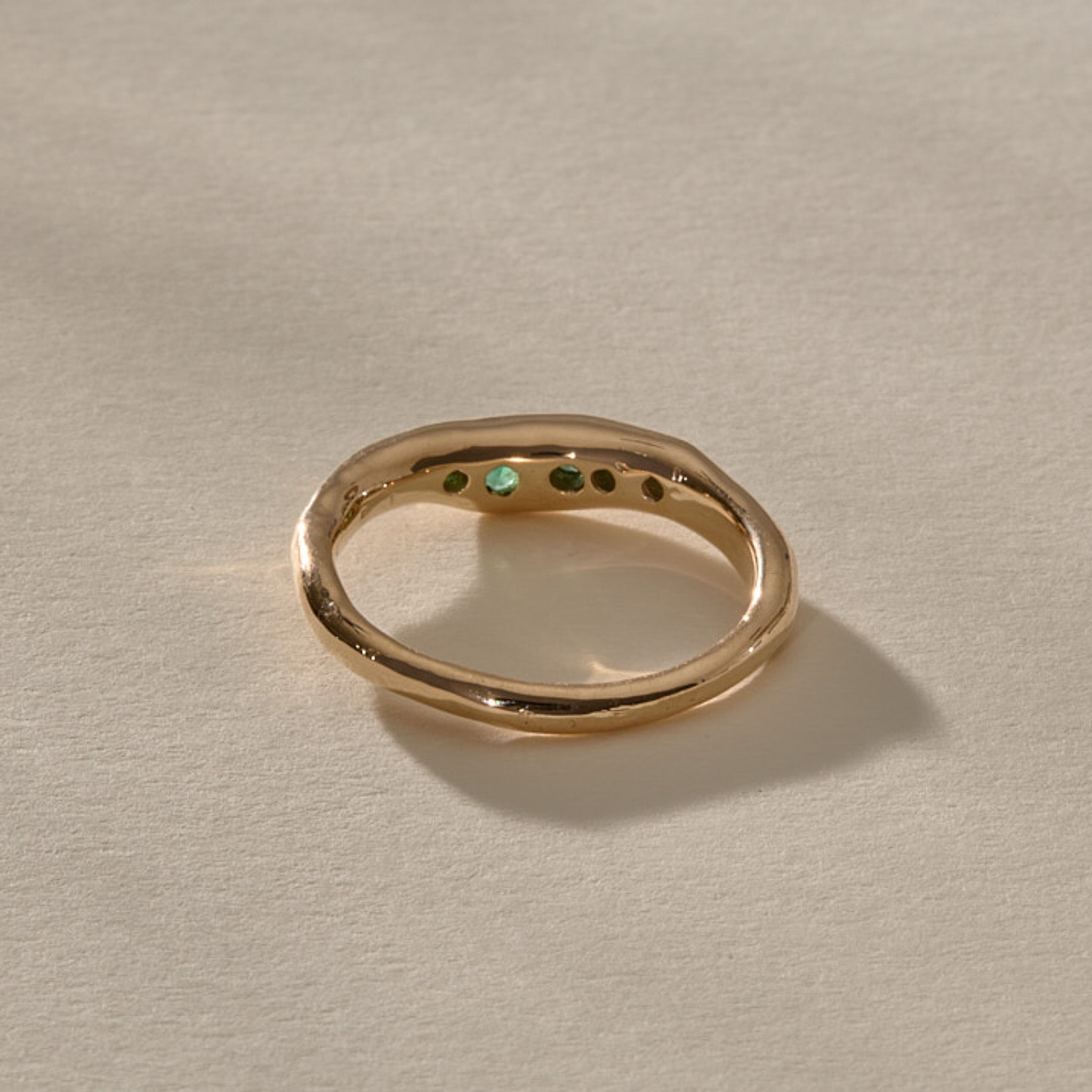 Eros Five-Stone Emerald Band in solid recycled gold from the back, showing the emeralds through the open settings.