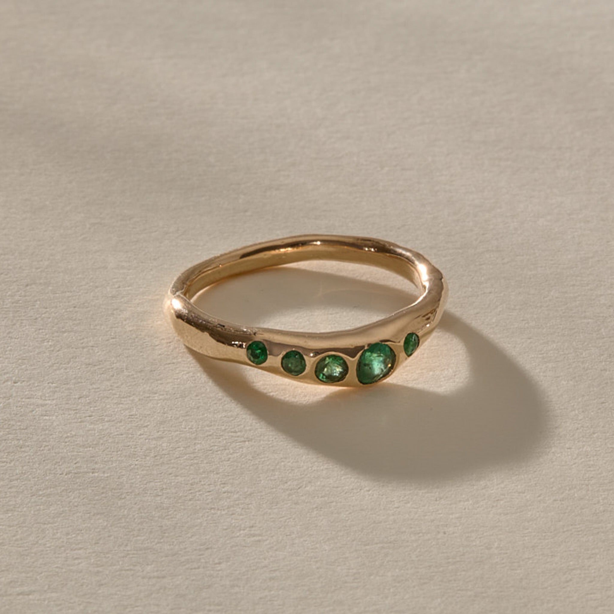 Eros Five-Stone Emerald Band in solid recycled gold, five faceted green emeralds set across an organic band.