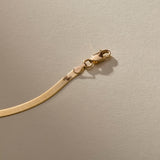 Close up of the gold Fehu Herringbone Chain Bracelet lobster clasp.