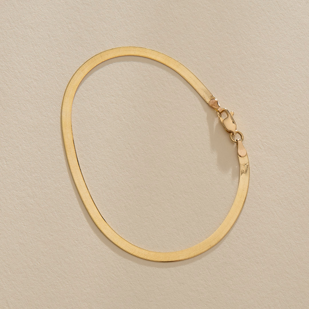 Fehu Herringbone Chain Bracelet in gold from above, fastened in an oval.