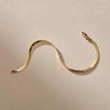 Fehu Herringbone Chain Bracelet in gold laid in a wave, showing the flat, shiny herringbone links.