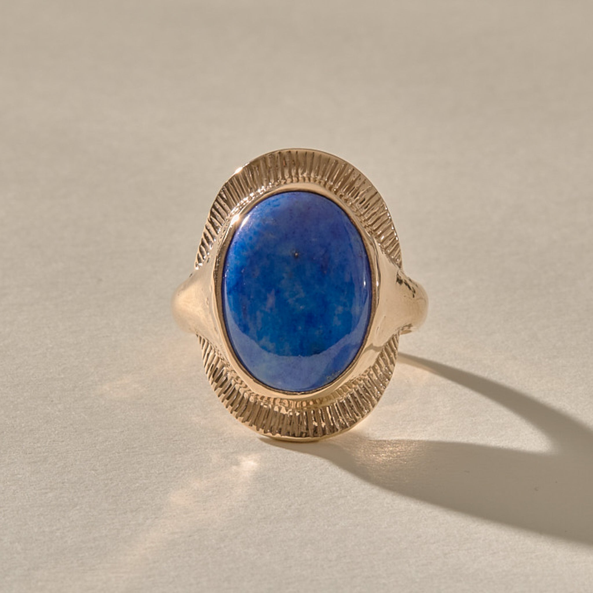 Inanna Lapis Shield Ring in gold from the front, showing the deep blue lapis with golden flecks inside its carved shield.