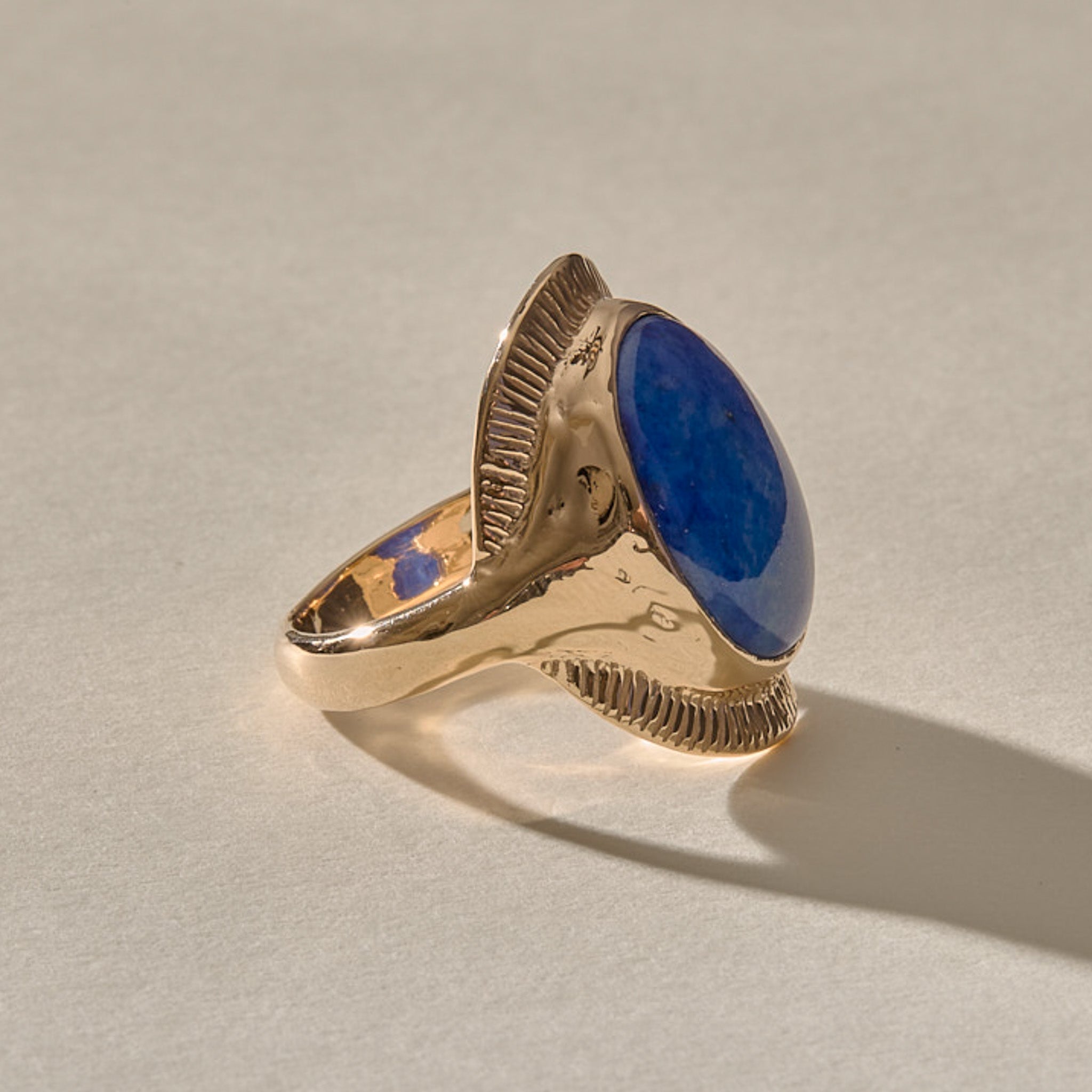 Inanna Lapis Shield Ring in gold from the side, showing the raised oval setting and carved shoulders.