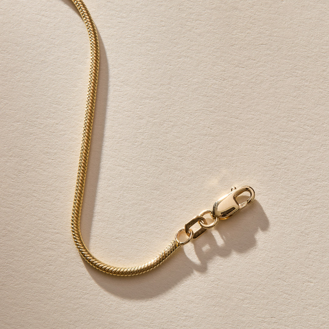Close up of the 14k gold Jera Snake Chain clasp and links.
