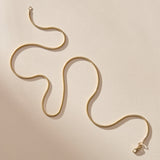 14k gold Jera Snake Chain, 1.55mm wide, laid in a flowing curve with its clasp.