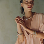 Model in a blush top wearing stacked Rustic Magi Bangles.