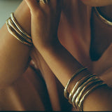 Rustic Magi Bangles stacked on the wrists in warm light.