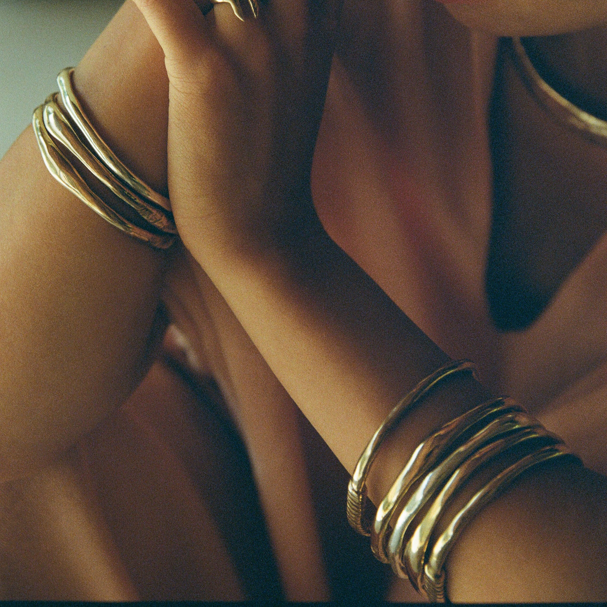 Rustic Magi Bangles stacked on the wrists in warm light.