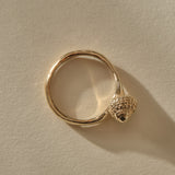 Top-down view of the Maré Shell Ring in gold, the seashell set to one side of the round band.