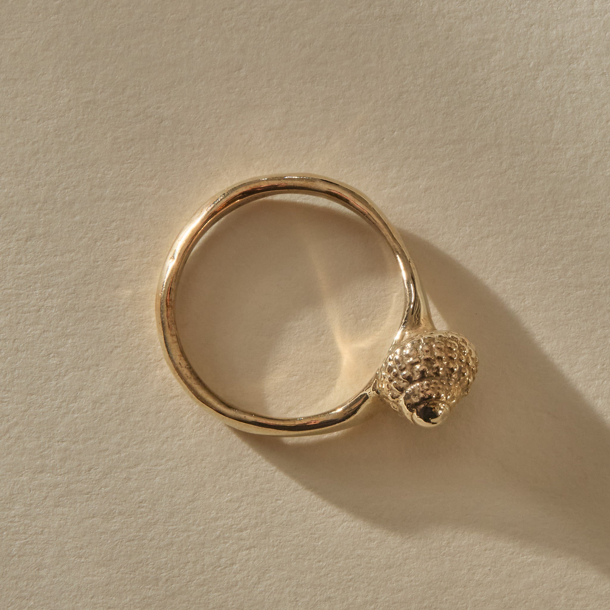 Top-down view of the Maré Shell Ring in gold, the seashell set to one side of the round band.