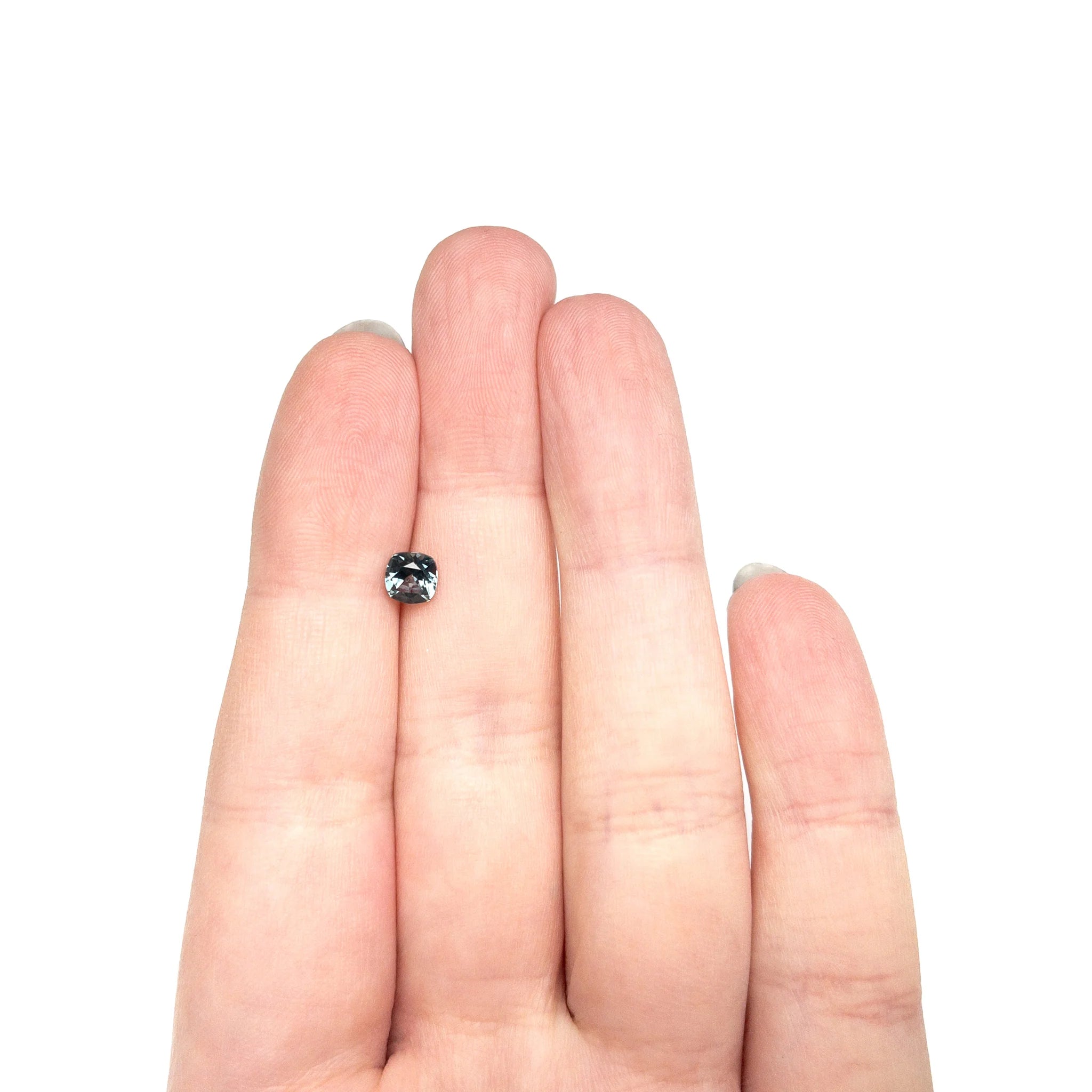 The loose Montana sapphire resting on fingertips to show its size.