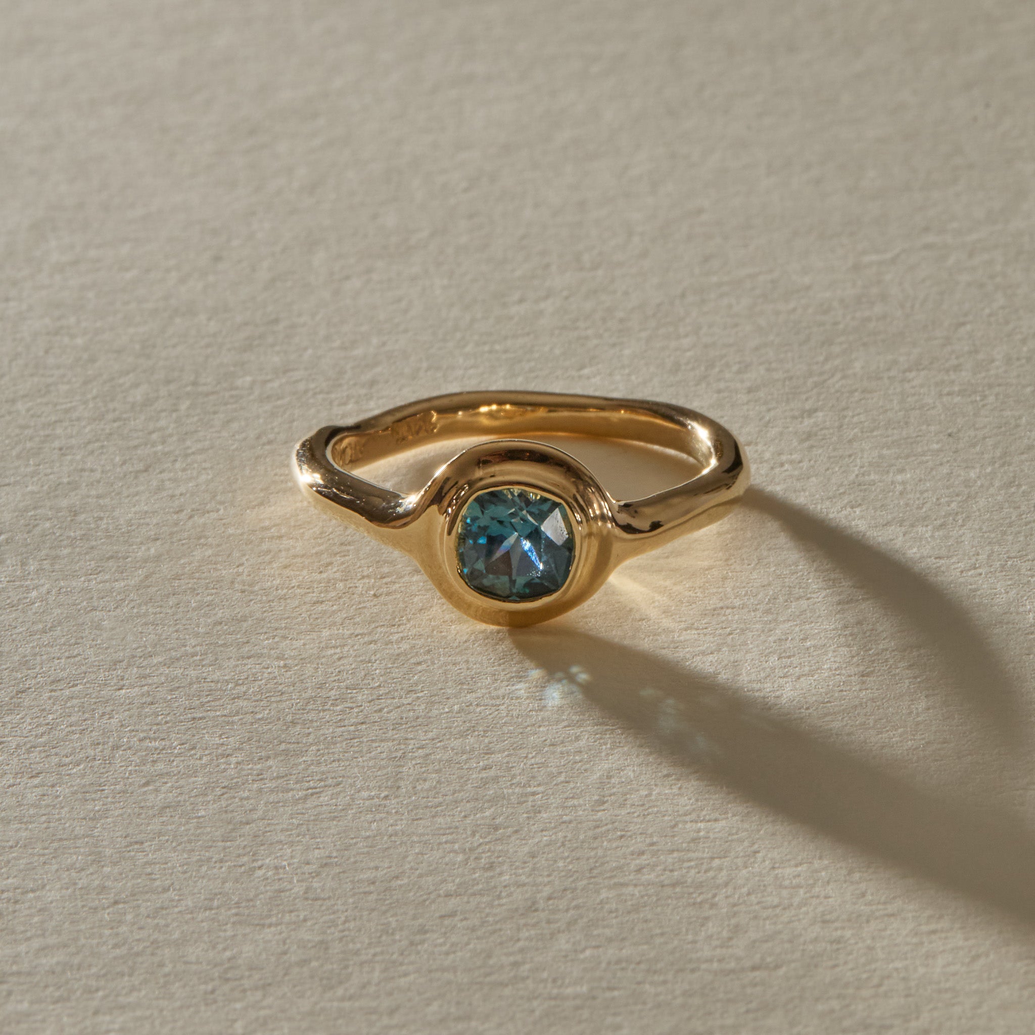 Meridian Montana sapphire ring from the front, showing the cushion cut stone in its rounded gold bezel.