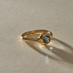 Meridian Ring in 14k recycled gold, a 0.82ct blue-teal cushion cut Montana sapphire in a bold bezel on an organic band, in warm sunlight.