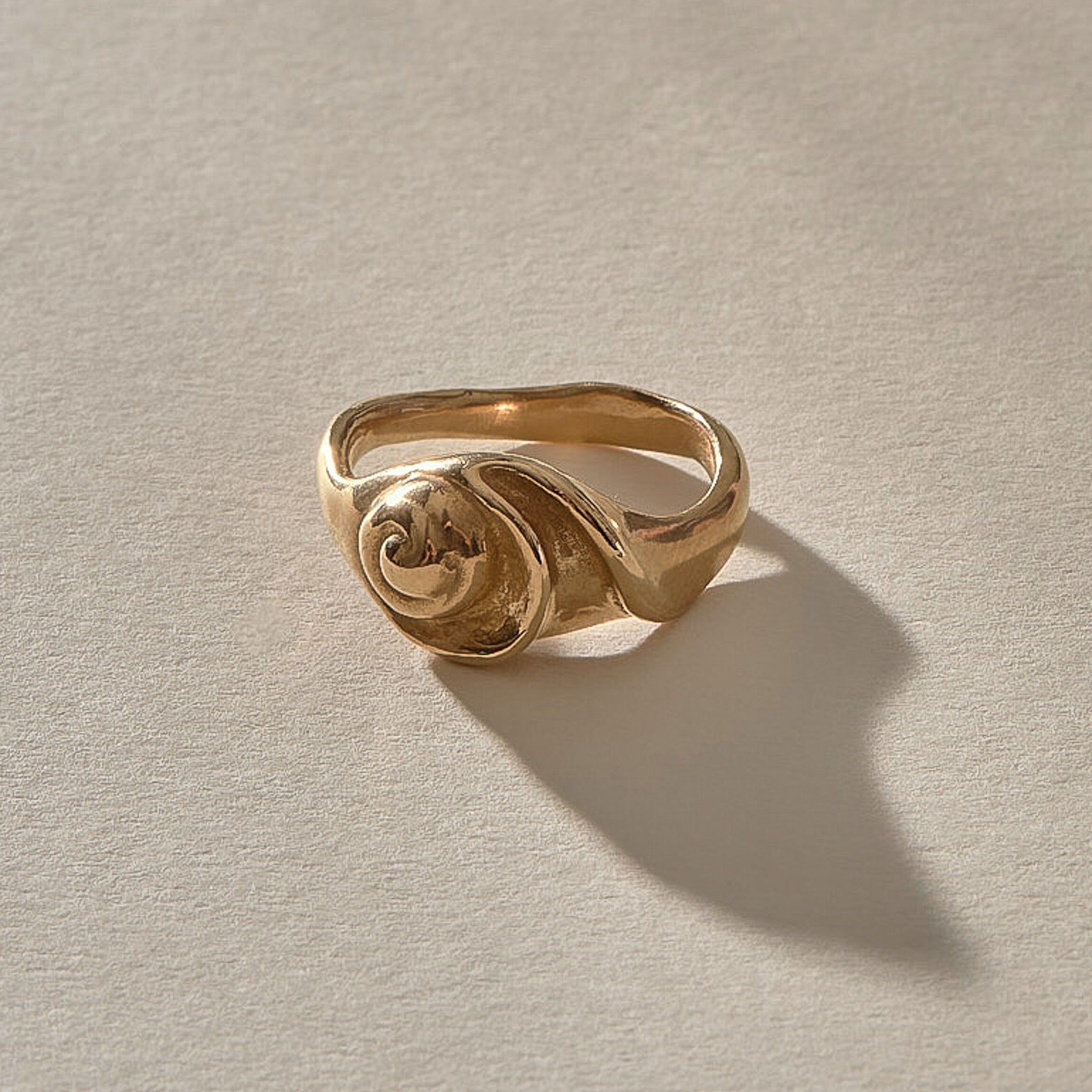 Neptune Spiral Shell Ring in gold, a hand-cast spiral seashell set on the band, seen from the front.
