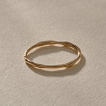 A single Nova stacking ring in solid gold, a delicate 1 to 1.5mm band with a gently uneven shape.