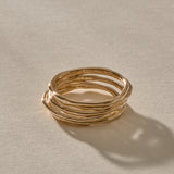 Nova Stacking Rings, a set of five thin, softly imperfect bands in solid recycled gold, stacked together in warm sunlight.