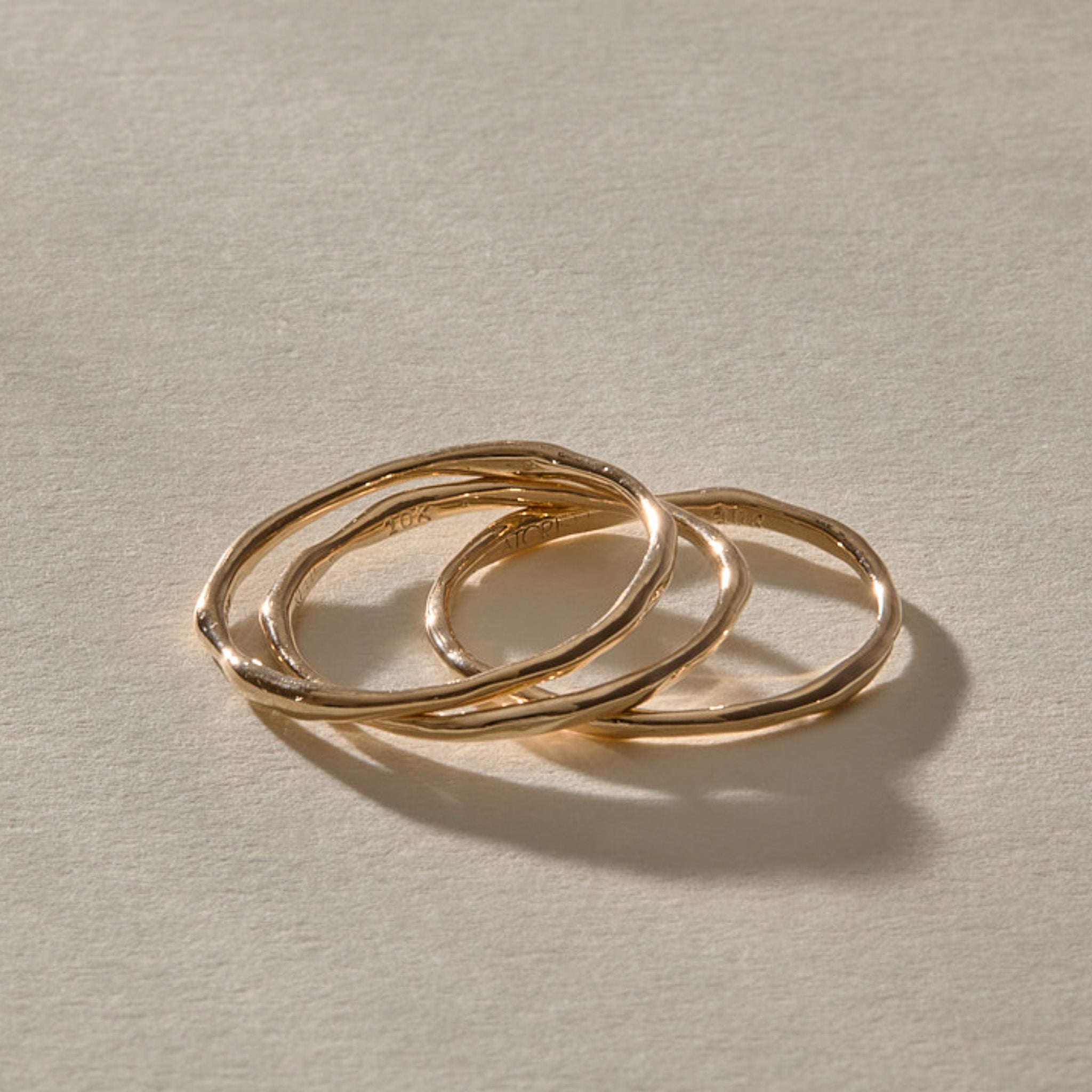 Nova Stacking Rings in solid recycled gold from the side, showing how the thin bands sit together.