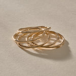 Five Nova gold stacking rings resting together, showing their organic, hand-formed shapes.